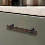 Minimalist walnut wood drawer handle on dark cabinet surface.