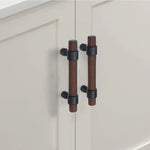 Walnut drawer handles with gold mounts on modern white cabinet doors.