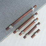 Set of walnut drawer handles in different lengths on gray background.