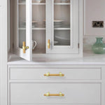 Wood drawer handles with silver brackets mounted on white cabinets.