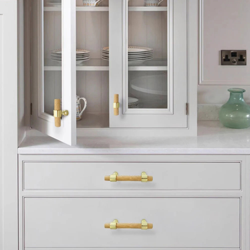 Wood drawer handles with silver brackets mounted on white cabinets.