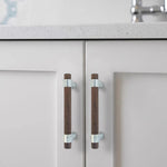 Pair of walnut wood drawer handles with black mounts installed on cabinet.