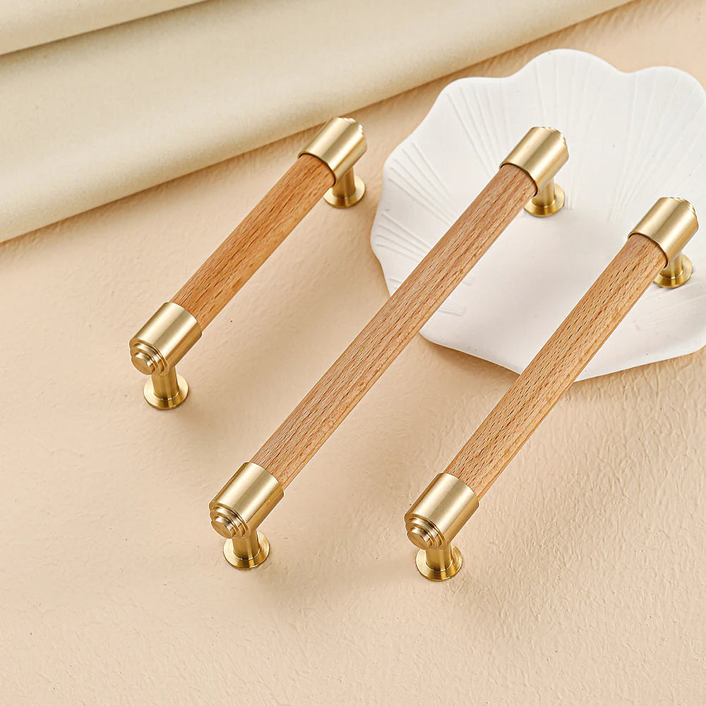 Light beech wood and brass crystal cabinet handles in a modern style.