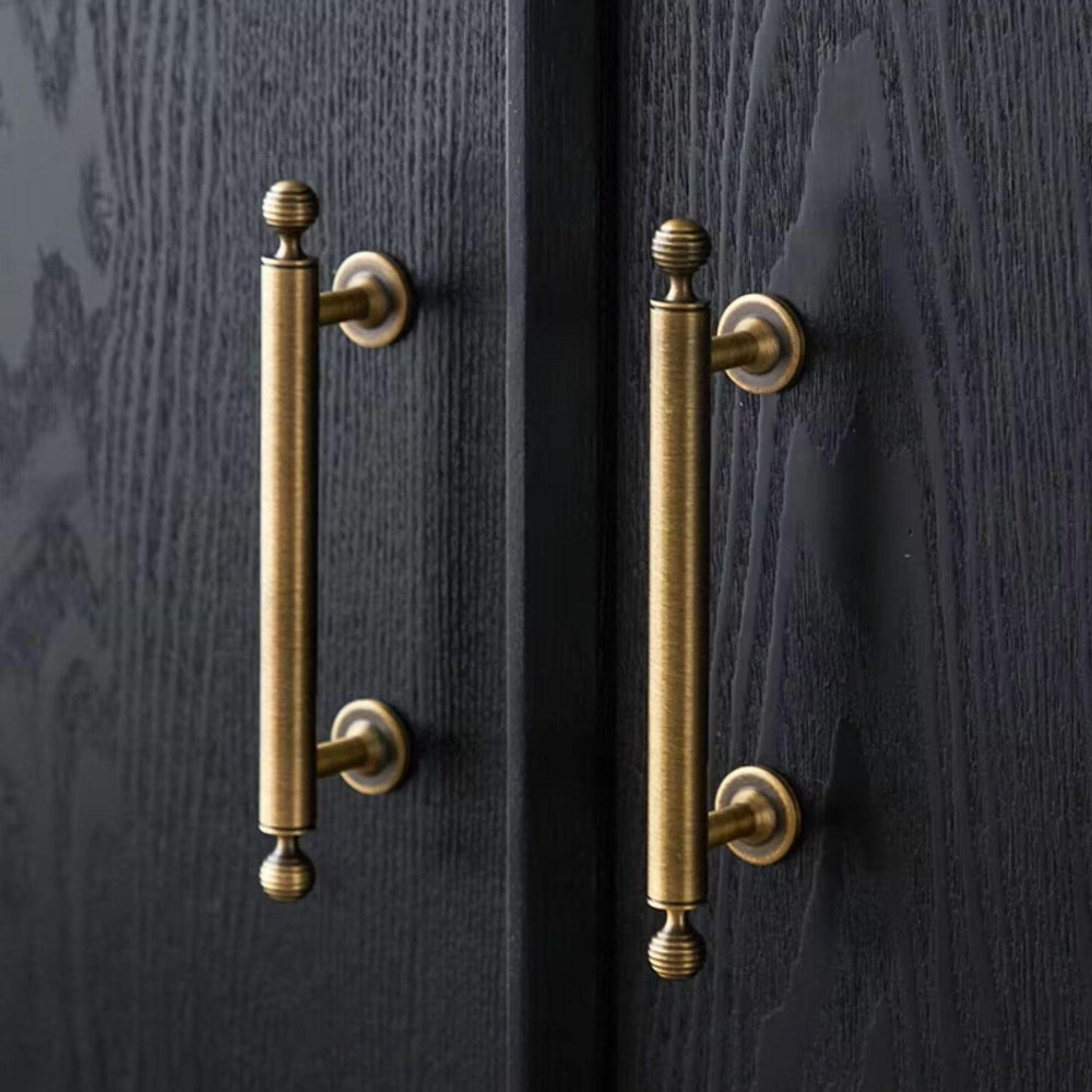 Pair of brass cabinet handles on a dark wooden door