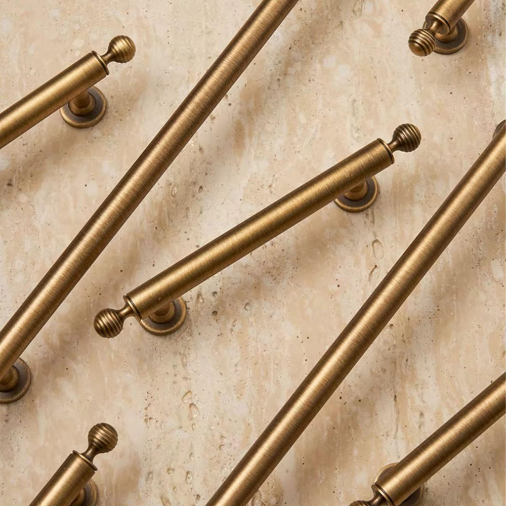 Collection of gold cabinet handles on a beige marble background