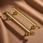 Two gold cabinet handles on a brown fabric background