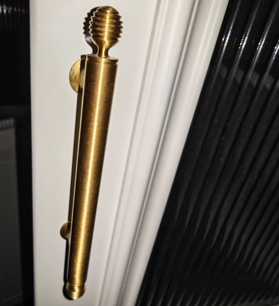 Brass door handle on a white door with black window