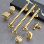 Collection of gold cabinet handles and knobs on a gray surface