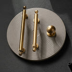Gold cabinet handles on a textured gray surface with a dark background