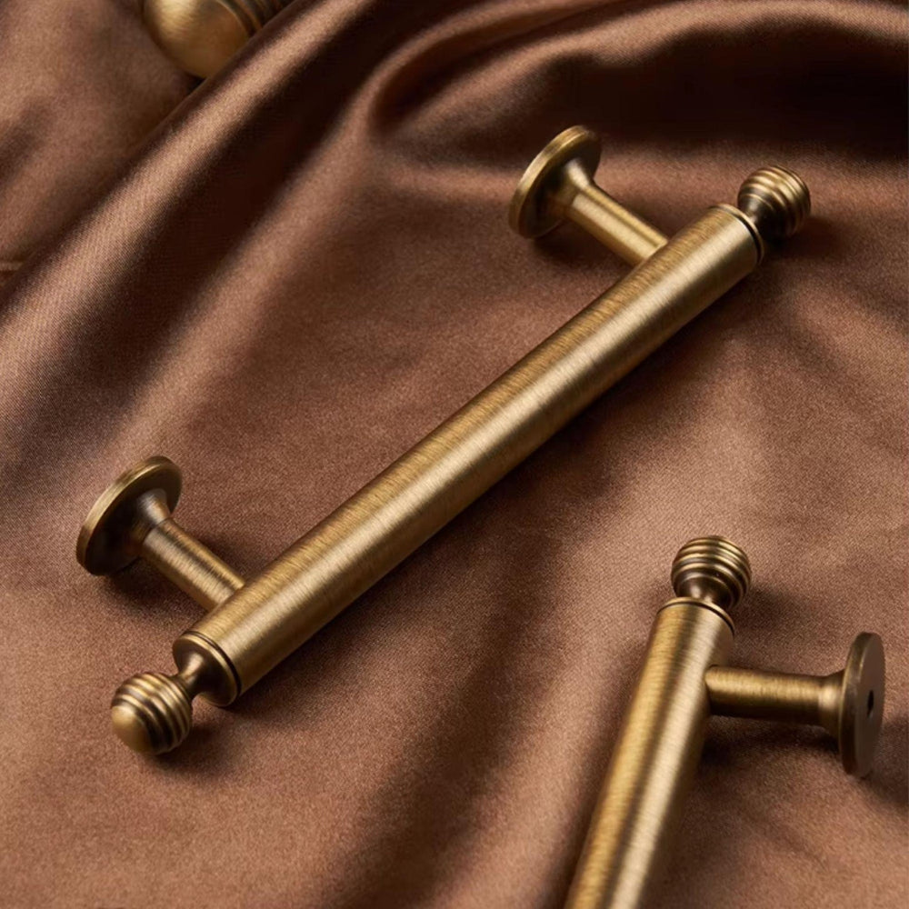 Three gold cabinet handles on a brown fabric background