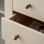 Close-up of a cabinet with brass knobs and open drawer revealing magazines.