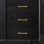 Black dresser with gold handles on a dark background
