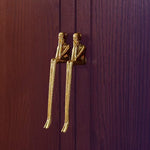 Gold door knocker shaped like two people sitting on a wooden door