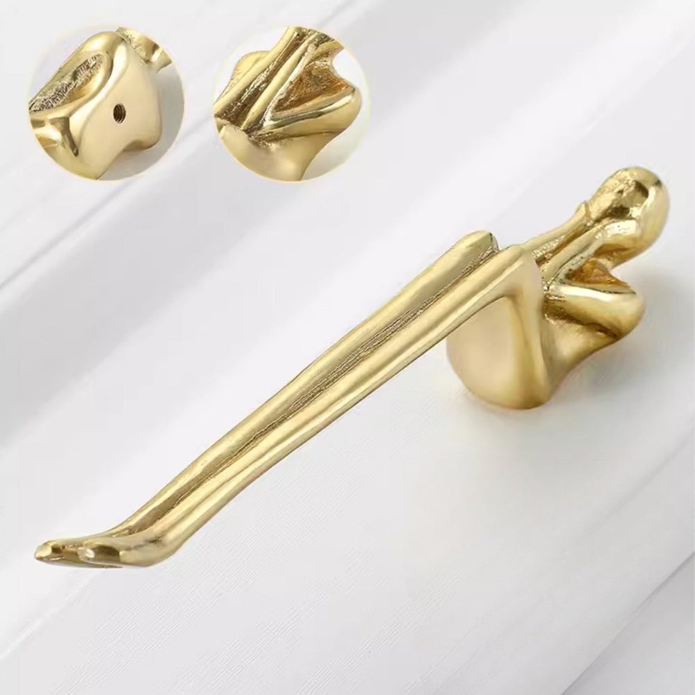 Gold decorative item resembling a winged figure on a white background