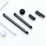 Black and white cylindrical objects on a white surface with a patterned paper in the background