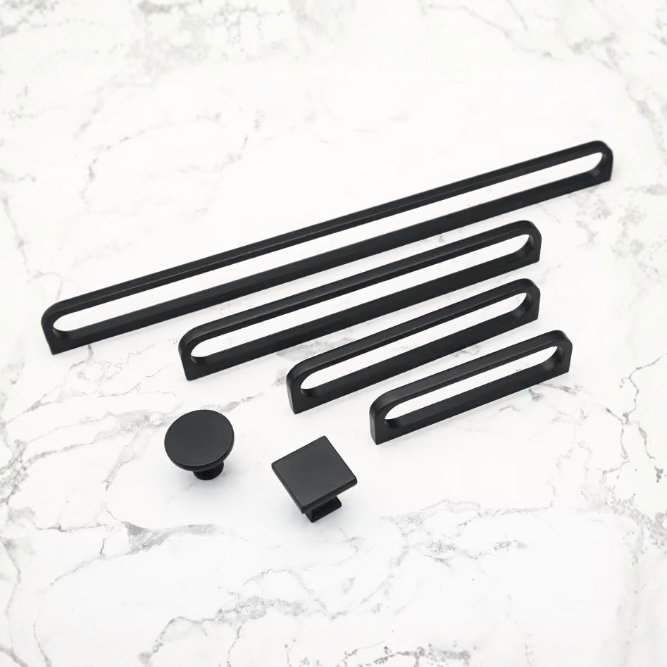 Set of black cabinet knobs and handles on a marble surface