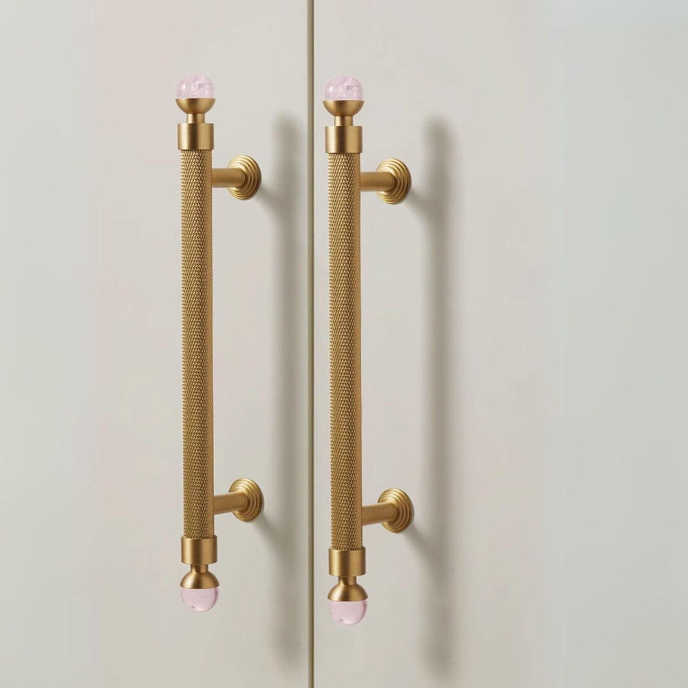 Gold door handles with pink knobs on a white background