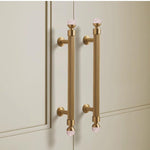 Gold cabinet handles on a light-colored cabinet door