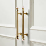 Gold cabinet handles with pink knobs on a white paneled door