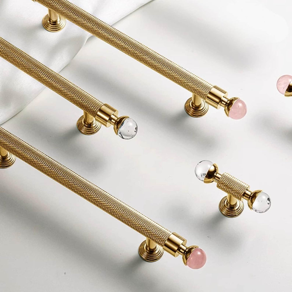 Gold mesh handles with pink and clear knobs on a white background