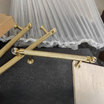 Gold handles on a piece of furniture with a curtain in the background