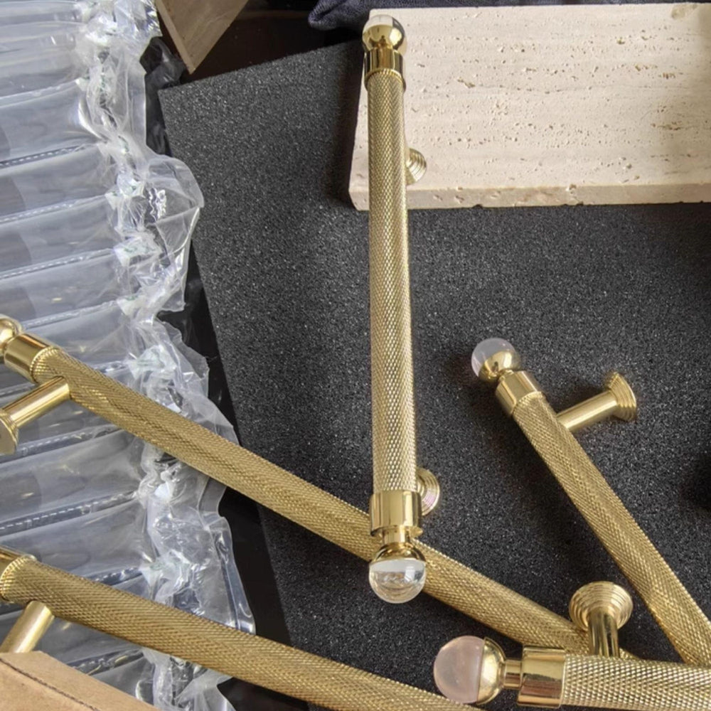 Gold door handles on a black foam block with packaging materials in the background
